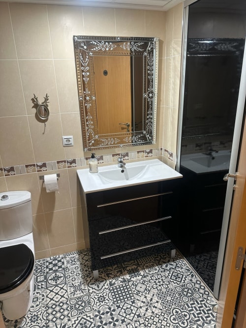 Baño moderno del apartamento Golf Panorámica en Sant Jordi, con vanitory negro, piso de azulejos decorativos y espejo ornamentado