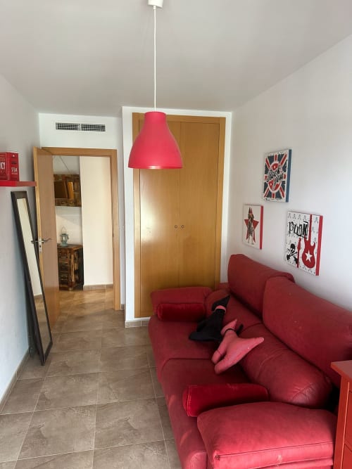 Sala de estar moderna con sofá rojo, lámpara colgante rosa y puertas de madera en Sant Jordi
