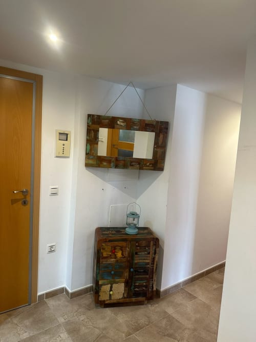 Entrada del pasillo del apartamento Sant Jordi con espejo de madera, mueble y piso de baldosas