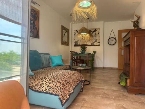 Dormitorio moderno en Sant Jordi con ropa de cama de leopardo, acentos turquesas, lámparas colgantes tejidas y vista a la montaña