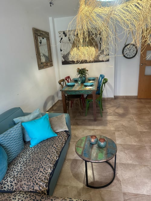 Acogedor salón del apartamento Sant Jordi con sofá turquesa, mesa de comedor y decoración moderna con vistas a la montaña