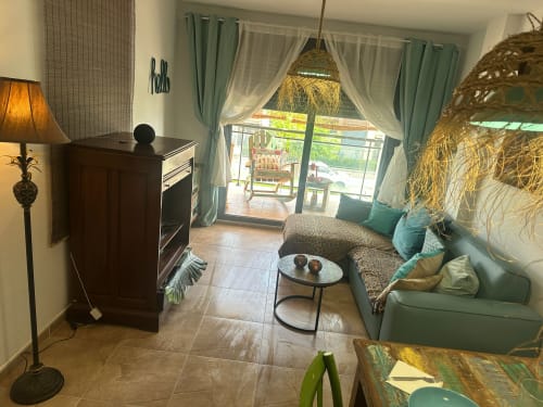 Salón moderno con cortinas verdes, muebles cómodos y vistas a las montañas a través de puertas de cristal en Sant Jordi