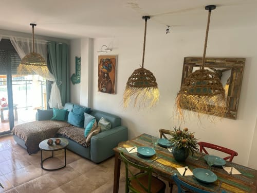 Acogedor salón del apartamento Sant Jordi con sofá turquesa, mesa de comedor y lámparas colgantes tejidas