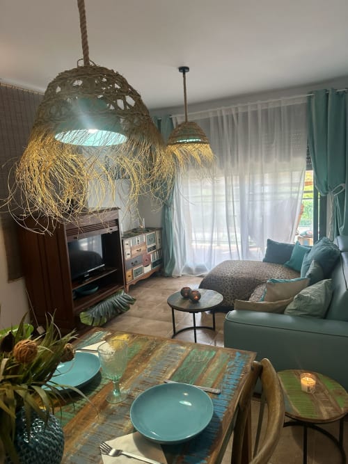 Moderno salón de apartamento con acentos turquesas, mesa de comedor, iluminación colgante y vistas a las montañas de Sant Jordi