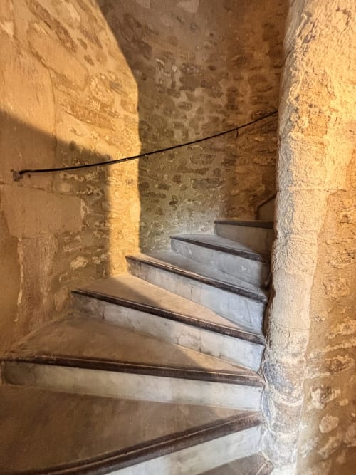 Escalier en pierre avec rampes métalliques dans la charming maison d'hôtes historique Entre Ciel et Lettres, menant vers le haut à travers une ambiance rustique