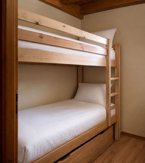 Wooden bunk bed with white bedding in Le Chalet des Cimes apartment, Belle Plagne