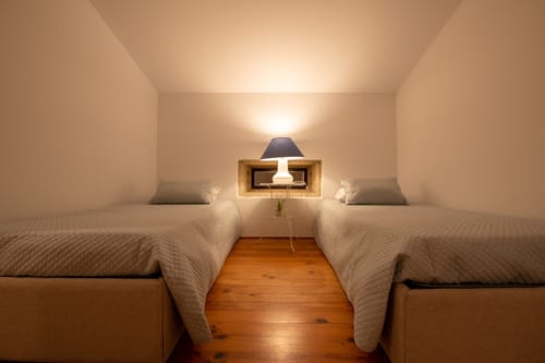 Quarto duplo com camas de madeira e iluminação aconchegante na Quinta da Malaposta Boutique Hotel em Vila Nova de Cerveira, Portugal
