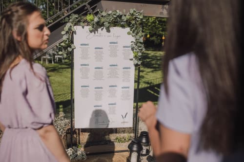 Convidados de casamento visualizando o quadro de lugares com guirlanda de vegetação na Quinta da Malaposta Boutique Hotel em Vila Nova de