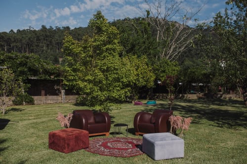 Área de estar exterior com poltronas e otomanas bordô em gramado bem cuidado na Quinta da Malaposta Boutique Hotel, Vila Nova