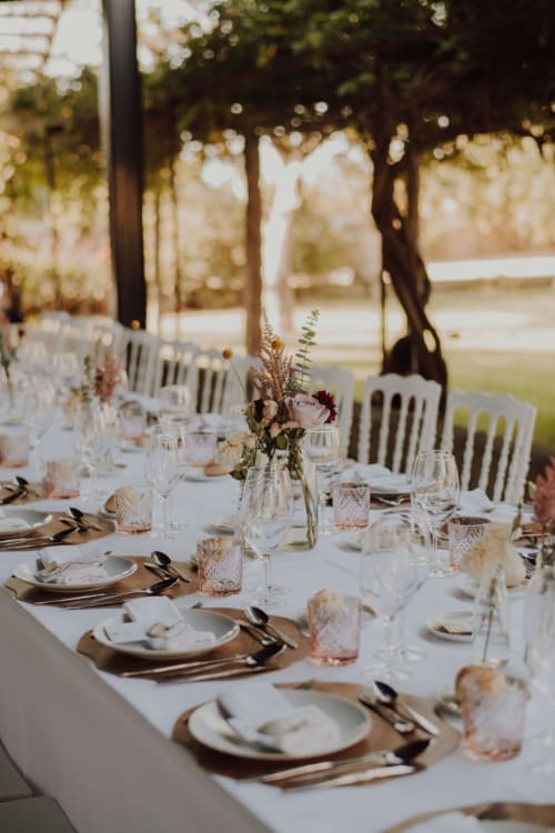 Mesa de banquete elegante ao ar livre com toalhas brancas, postos de mesa e arranjos florais na Quinta da Malaposta, Vila Nova de