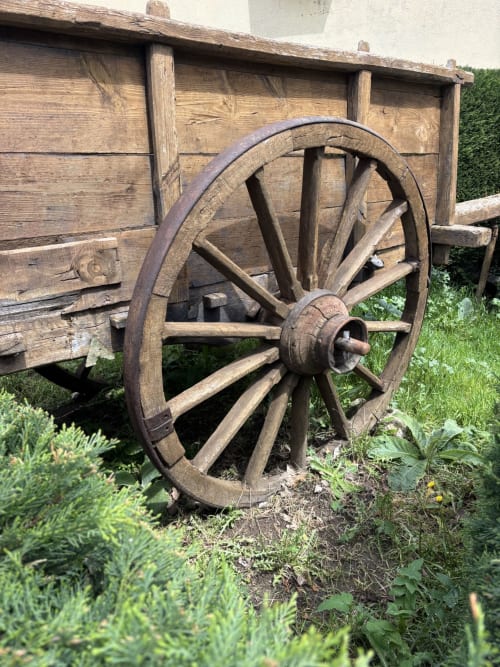 Rustic wooden cart with large weathered wheel at Casa Baelo Claudia rural villa in Navalguijo, Spain