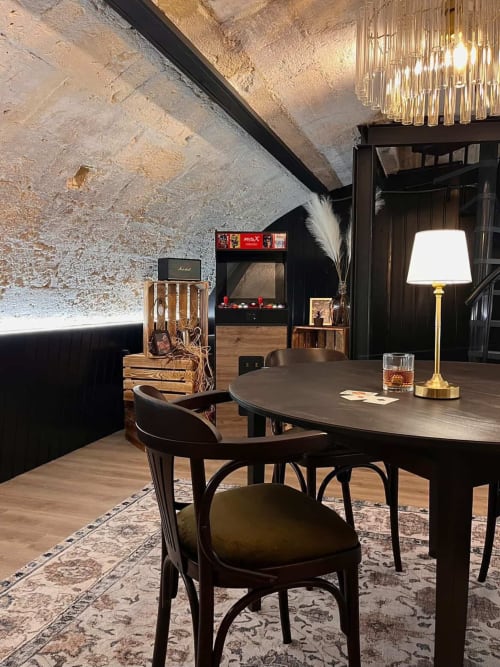 Modern Bordeaux apartment lounge with dark wood desk, black chairs, and exposed stone ceiling
