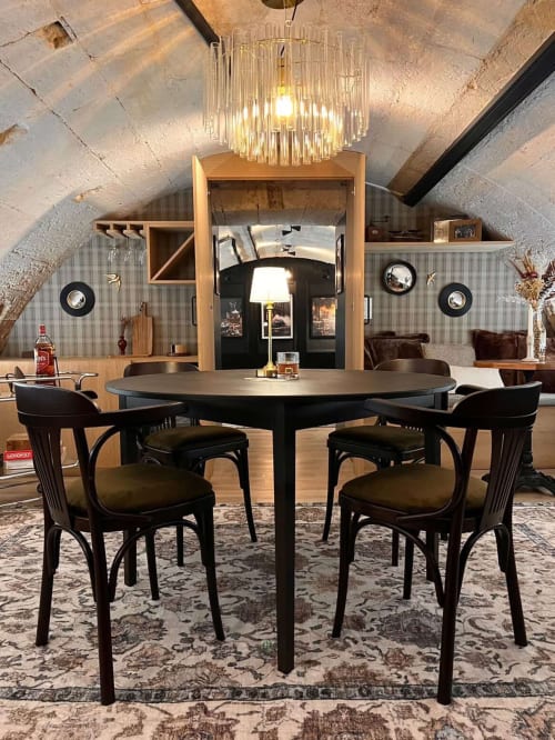 L'Arcade Secrète apartment dining area with round black table, black chairs, crystal chandelier, and wooden shelving in