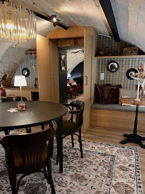 L'Arcade Secrète apartment in Bordeaux with dining area, round table, wooden wardrobe, and striped wallpaper decor