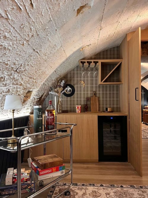 Stylish attic apartment bar area in Bordeaux with wooden cabinetry, wine cooler, and sloped stone ceiling