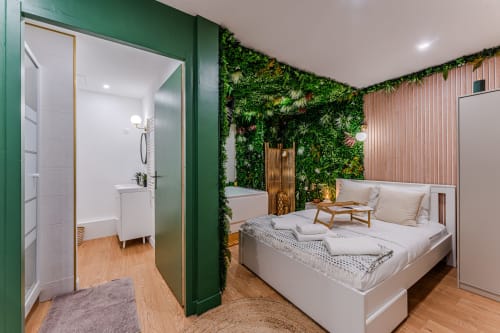LA BOÉTIE apartment at Wellkhome Bordeaux featuring bedroom with white bed, green living wall, ensuite bathroom and city view