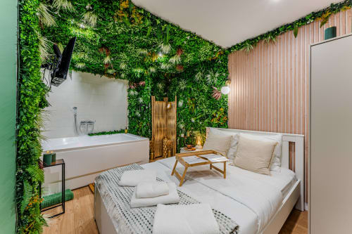 La Boétie apartment in Bordeaux with bed, bathtub, living area, and lush green wall plants