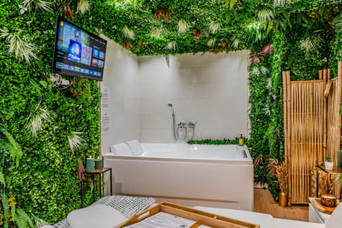 Modern bathroom with lush green living walls, soaking tub, and flat-screen TV at Wellkhome Bordeaux apartment La Boétie