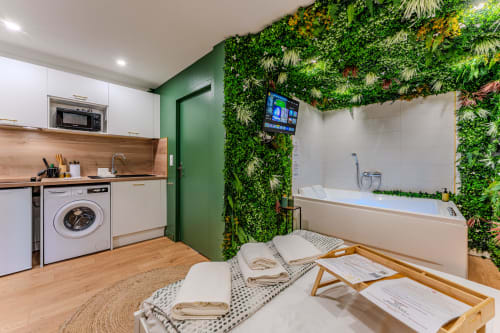Modern studio apartment at Wellkhome Bordeaux with kitchenette, living area, bathtub, and green living wall accent