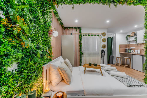 Wellkhome LA BOÉTIE apartment in Bordeaux with lush green living walls, modern bed, kitchenette, and city-view balcony