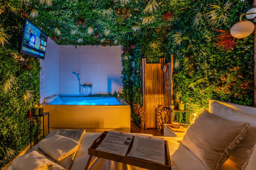 Luxury apartment bathroom at Wellkhome Bordeaux with illuminated yellow bathtub, green plant walls, and blue ambient lighting