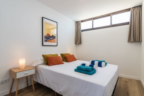 Bright bedroom at Home Stay Gran Canaria with sea view, white bed, colorful pillows, nightstand, and modern furnishings
