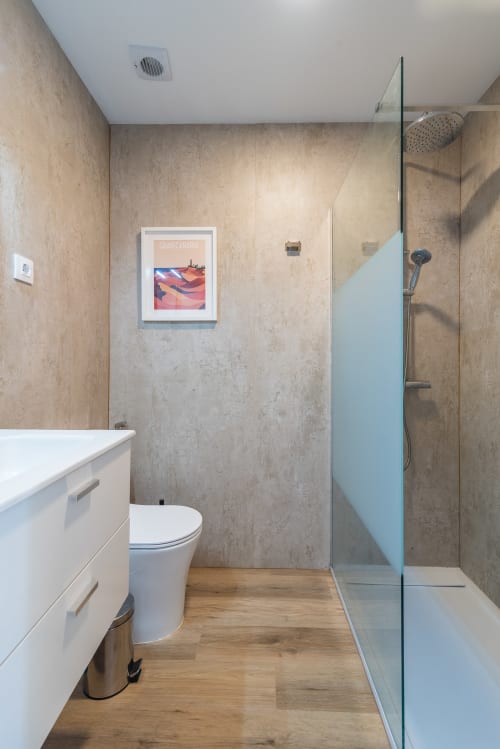 Modern bathroom in Gran Canaria apartment with walk-in shower, white vanity, and framed wall art