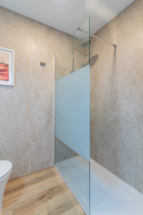Modern bathroom with walk-in shower, travertine tiles, and wooden flooring in Cactus Dunes Seaview apartment, Gran Canaria