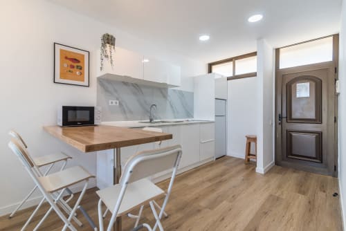 Modern kitchen and dining area in Cactus Dunes Seaview apartment, Gran Canaria, with white cabinetry and wooden countertop.
