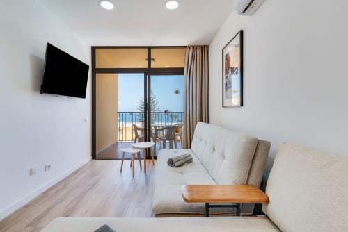Modern sea view apartment living room with sofa, TV, balcony overlooking ocean in Gran Canaria