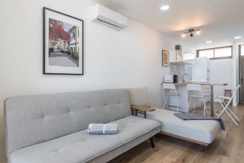 Modern living room with gray sofa, kitchenette, and sea view artwork at CACTUS DUNES apartment in Gran Canaria