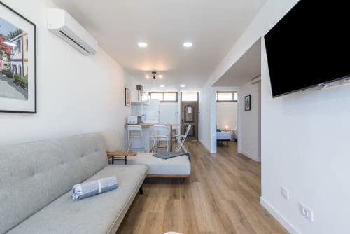 Bright modern apartment living area with gray sofa, dining table, TV, and sea views in Gran Canaria
