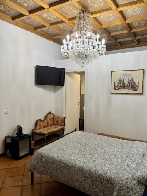 Elegante camera doppia Deluxe da Domus Giovanna Roma con lampadario in cristallo, pavimenti in marmo e vista sulla corte interna