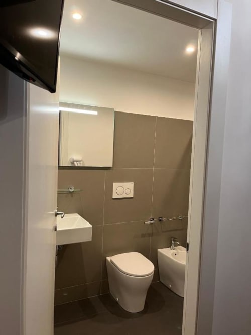 Bagno moderno dell'hotel Domus Giovanna a Roma con toilette, bidet, lavabo e specchio con pareti piastrellate