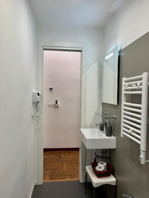 Bagno moderno di Domus Giovanna Roma B&B con lavabo bianco, scaldasalviette e vista sul corridoio con parquet