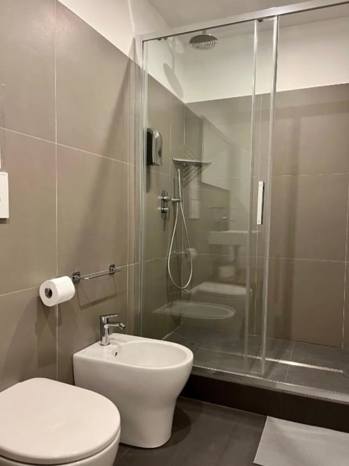 Bagno moderno in Domus Giovanna Roma B&B con doccia in vetro, bidet, wc e rivestimento in piastrelle beige