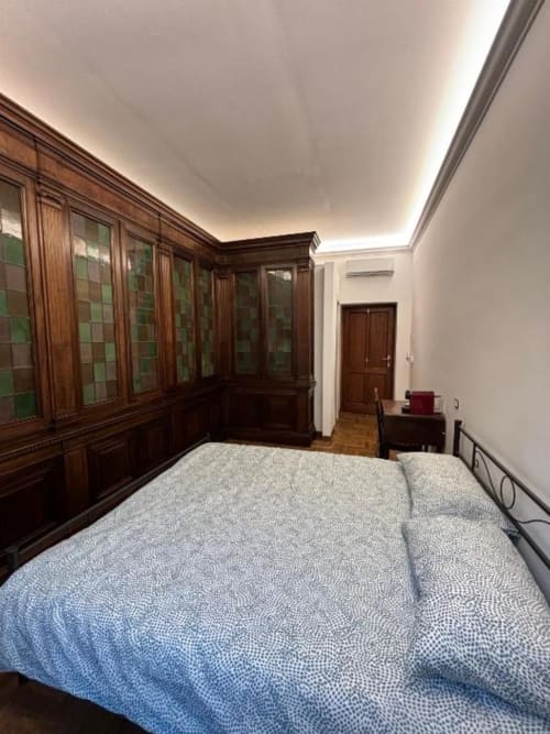 Elegante camera doppia a Domus Giovanna Roma con armadio in legno scuro, soffitto luminoso e vista sulla città