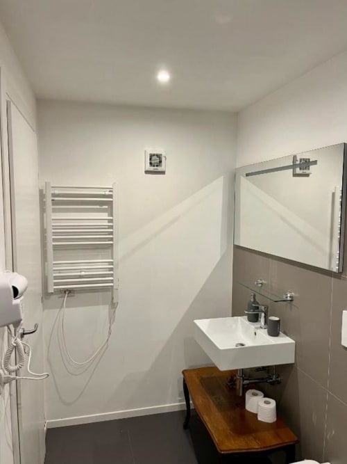 Bagno moderno in Domus Giovanna Roma BnB con lavabo bianco, scaldasalviette, specchio e pareti piastrellate