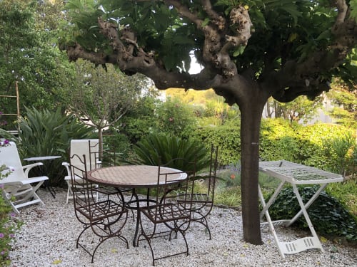 Terrasse ombragée de la Villa Gecko à Saint-Raphaël, mobilier en fer forgé sous un arbre noueux et verdure luxuriante