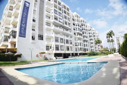 Moderno complejo residencial en Fuengirola con piscina y palmeras, propiedad de Grupo Inmohouse