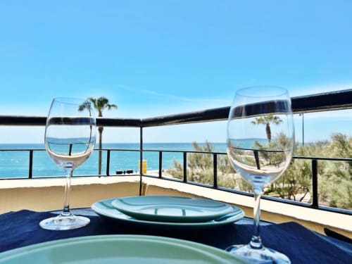 Terraza de comedor frente al mar en Fuengirola con copas de vino con vistas al Mediterráneo y palmeras