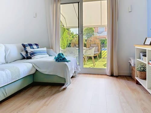 Dormitorio luminoso en la casita Mar Blau con cama, puertas al jardín, suelo de madera y vistas encantadoras