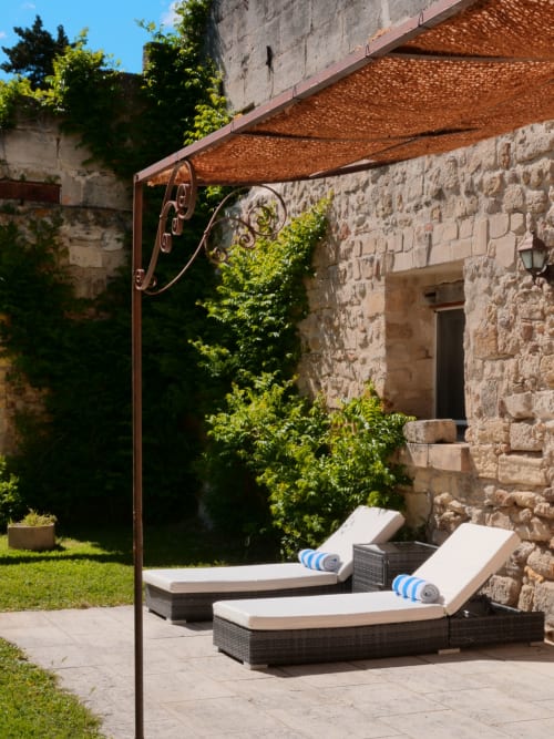 Lounge ombragé du Mas Petit Prince à Arles avec murs en pierre et transats