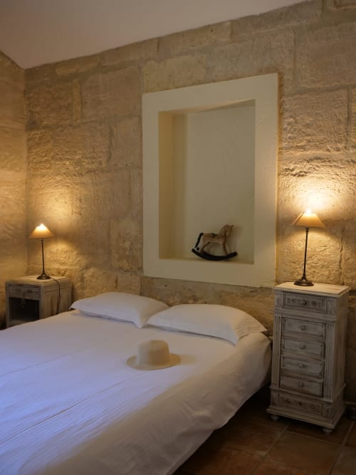 Chambre rustique en pierre au Mas Petit Prince, Arles avec lit blanc, éclairage chaleureux et niche décorée
