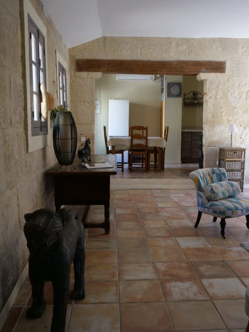 Spacieux séjour du gîte d'Anna au Mas Petit Prince à Arles, avec murs en pierre, carrelage en terre cuite et mobilier rayé