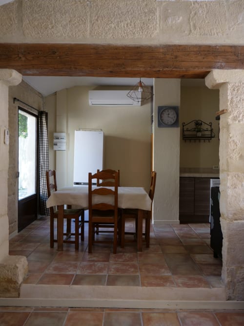 Salle à manger du gîte d'Anna au Mas Petit Prince à Arles, avec table en bois, carrelage en terre cuite et poutres apparentes
