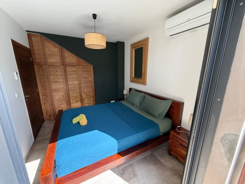 Chambre moderne avec literie bleue, armoire en bois et mur d'accent foncé au gîte Les Hébergements Passion, Les Trois-Ilets