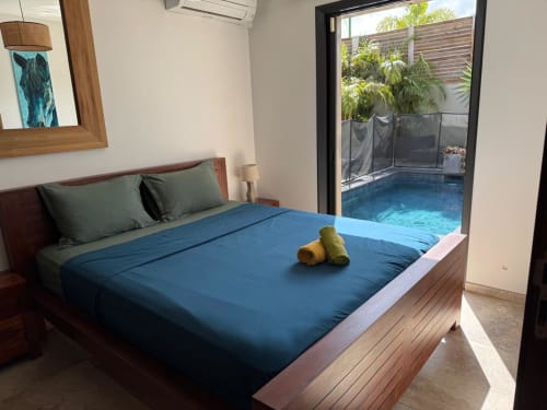Chambre moderne avec linge de lit bleu, meubles en bois et accès direct à la piscine privée du gîte Les Hébergements Passion
