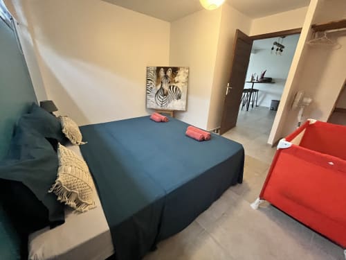 Chambre de la maison d'hôtes Les Hébergements Passion avec lit bleu, coffres de rangement rouges, art zèbre et salon ouvert