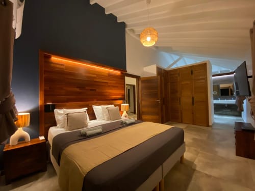 Chambre luxueuse avec tête de lit en bois et éclairage d'ambiance aux Hébergements Passion, Les Trois-Ilets